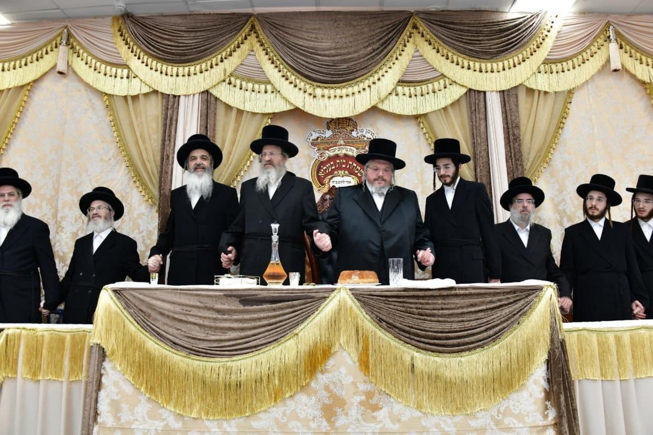 A group of men in black hats stands behind a decorated table